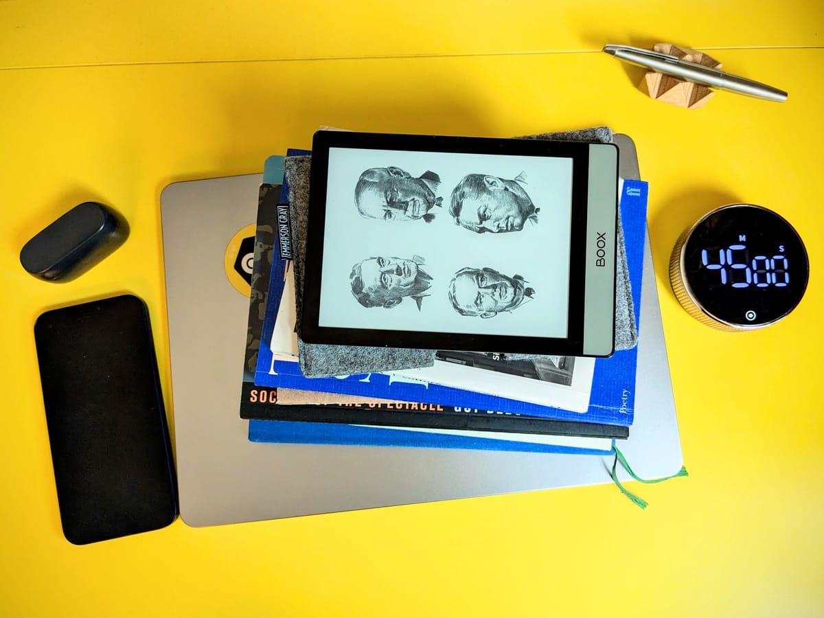 Items on a working desk including a laptop, mobile, timer and various books.